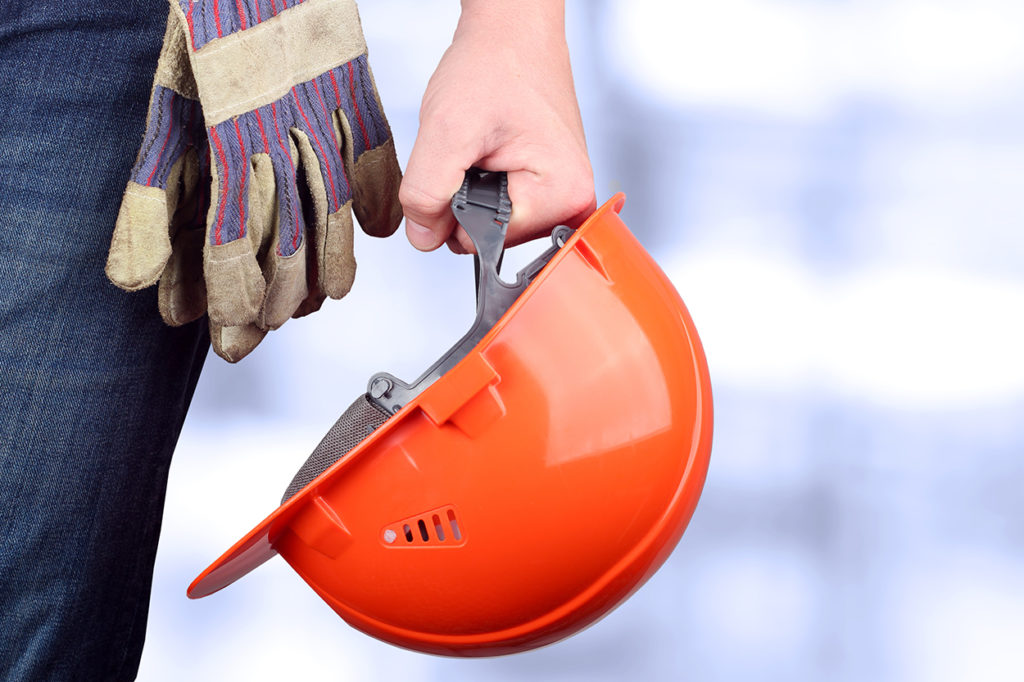 A worker hold onto their hard hat