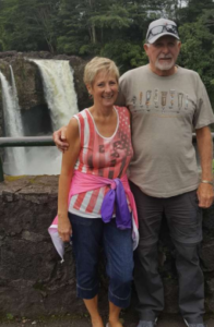 John Stahl and his wife stand together in front of a waterfall